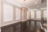 Elegant living room with dark hardwood floors, large windows with blinds, and a modern chandelier.