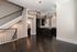 Elegant open-concept living area with dark wood floors, modern kitchen, and stylish staircase.