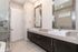 Luxurious modern bathroom featuring dual sinks with sleek chrome fixtures, elegant large mirrors, and a spacious shower with stylish tile accents.