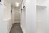 Elegant walk-in closet with ample shelving and hanging space, featuring sleek white cabinetry and modern lighting.