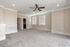 Spacious and elegant living room with plush carpeting, ceiling fan, and large windows for natural light.