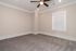 Bright and airy room with a modern ceiling fan on a beige carpet, featuring elegant crown molding and large window blinds.