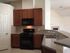 Modern kitchen with sleek granite countertops, wooden cabinets, and an integrated stove and microwave.