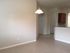 Bright open space with modern tile flooring and elegant light fixture, featuring an inviting hallway leading to a warm kitchen area.