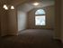 Inviting living space with plush carpet, elegant chandelier, and large arched window offering ample natural light.