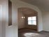Inviting living space with arched doorway, soft carpeting, and ample natural light from large window.