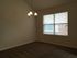 Cozy room featuring soft carpet flooring, large window with blinds offering natural light, and elegant ceiling light fixture.
