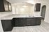 Elegant kitchen with dark cabinetry, light marble countertops, and modern appliances in a spacious open-plan layout.
