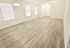 Spacious empty room with elegant wood flooring, large windows, and ample natural light, perfect for customization.