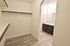Spacious walk-in closet with elegant wood flooring and ample storage, leading into a modern bathroom with a sleek vanity.
