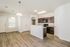 Bright open-plan kitchen with modern cabinetry, marble countertops, and elegant pendant lighting on stylish wooden flooring.