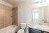 Modern bathroom featuring elegant tile work, a sleek vanity with a granite countertop, and ample natural light.