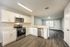 Modern open-plan kitchen and living area featuring sleek white cabinets, stainless steel appliances, and elegant wood flooring.