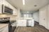 Modern kitchen with sleek white cabinets, stainless steel appliances, and open layout extending into a bright living area with hardwood floors.