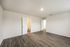 Spacious room with elegant wood flooring and white walls, featuring two open doors leading to a bathroom and hallway, ideal for modern living.