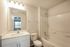 Bright and modern bathroom featuring sleek vanity, elegant lighting, and pristine bathtub with tile surround.