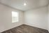 Bright, modern room with sleek hardwood floors and ample natural light from a large window, perfect for a cozy bedroom or home office.