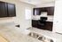 Modern kitchen with sleek dark cabinets, stone countertops, stainless steel sink, and a classic black oven. Bright and welcoming with natural light.