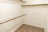 Spacious walk-in closet with wooden rods and modern laminate flooring, ideal for stylish storage solutions.