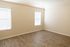 Bright and spacious room with stylish wood-look flooring and large windows with blinds, perfect for creating a cozy and inviting living space.