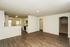 Bright open-plan apartment featuring a modern kitchen, hardwood floors, and arched entry to carpeted stairs.