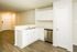 Modern kitchen with sleek white cabinetry, stainless steel dishwasher, and open floor plan leading to living area.