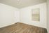 Bright, empty room with elegant wooden flooring and a window with blinds, perfect for customization.