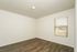 Bright bedroom with sleek wooden flooring and a large window, perfect for a serene living space.