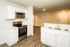 Modern kitchen with stainless steel appliances, elegant laminate flooring, and bright white cabinetry.