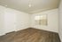Bright, spacious room with elegant wood flooring, large window for natural light, and fresh, neutral walls.