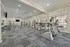 Modern apartment fitness center featuring state-of-the-art exercise equipment, spacious area with cardio machines, and bright natural lighting.
