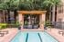 Charming outdoor pool area with elegant seating, surrounded by lush greenery and stylish brick architecture, ideal for relaxation and gatherings.