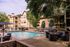 Luxurious apartment complex featuring a sparkling pool, elegant seating areas, and lush landscaping for a resort-style living experience.