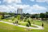 Vibrant urban park with lush greenery, jogging paths, and city skyline views, perfect for outdoor activities.
