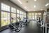 Bright and modern fitness center with large windows, treadmills, and elliptical machines set against a lush outdoor view.