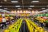 Vibrant grocery store showcasing fresh organic produce, with vibrant yellow bananas lining the aisles and a colorful fruit display. Shoppers enjoy a bustling yet organized shopping experience.