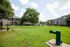 Inviting apartment complex with lush green lawn, mature trees, and charming two-story buildings, perfect for a serene lifestyle.