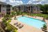 Inviting apartment complex with a crystal-clear pool, lush landscaping, and modern architecture, perfect for relaxation and leisure.