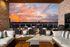 Stunning rooftop terrace with cozy seating and fire pits, offering a panoramic city view under a vibrant sunset sky.