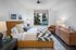 Sophisticated bedroom with elegant decor, featuring a plush bed, modern artwork, and a large window showcasing a pool view.