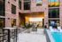 Luxurious apartment exterior showcasing a modern poolside with stylish lounge chairs, complemented by elegant brick architecture and inviting outdoor seating area.