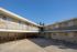 Bright exterior view of a two-story apartment building with a spacious courtyard and charming balconies.
