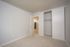 Modern bedroom with neutral walls, plush carpet, and a sliding door closet.
