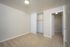 Bright empty bedroom with beige carpet and sliding closet doors.