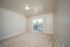 Bright empty room with plush carpet, neutral walls, and sliding glass door leading to a balcony.