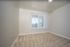 Inviting room with plush carpet and large window with vertical blinds.