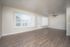 Spacious living room with large windows, hardwood floors, and ceiling fan in a modern apartment.