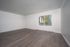 Bright empty living room with large window and stylish hardwood floor.