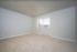 Inviting empty bedroom with soft beige carpeting and large window allowing natural light to brighten the space.
