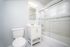 Bright and modern bathroom with sleek white vanity, elegant tiled shower, and contemporary lighting.